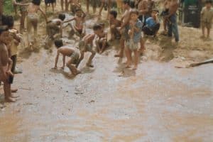 Tak się bawią dzieci miejscowe nad brzegiem rzeki zjeżdżając po błocie do wody